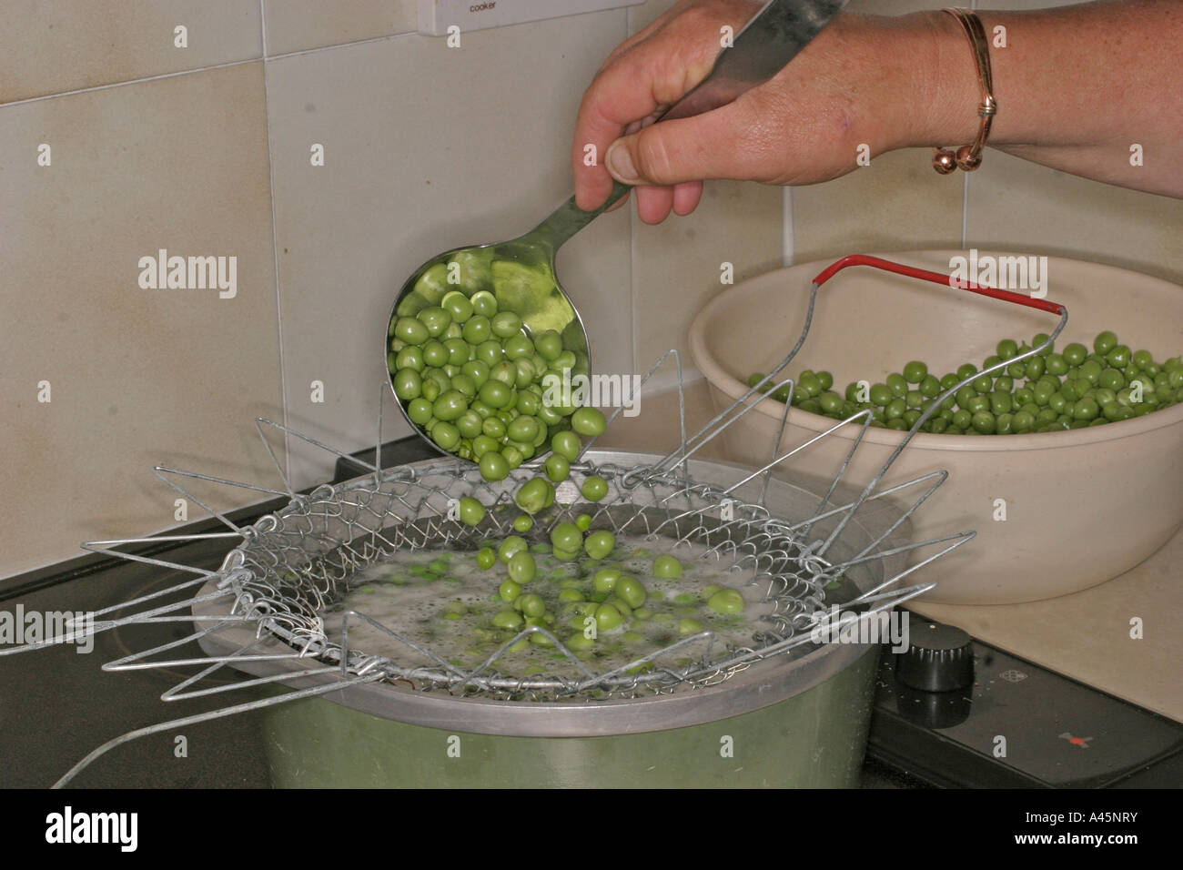 FREEZING PEAS STEP 1 LADLE RAW PEAS INTO BOILING WATER Stock Photo Alamy