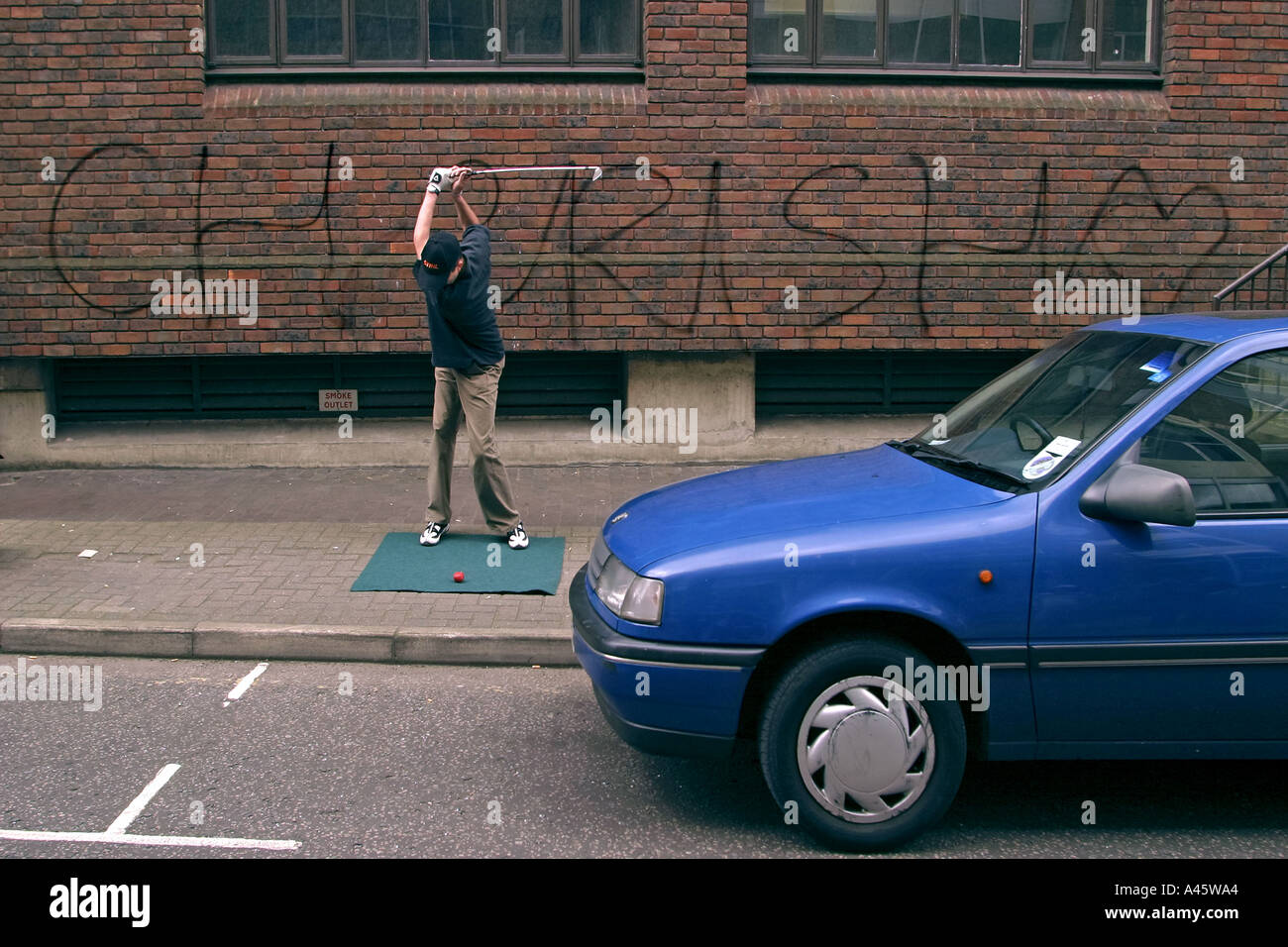 an urban golf competitor tees off in the street at the first shoreditch urban open tournament in london Stock Photo