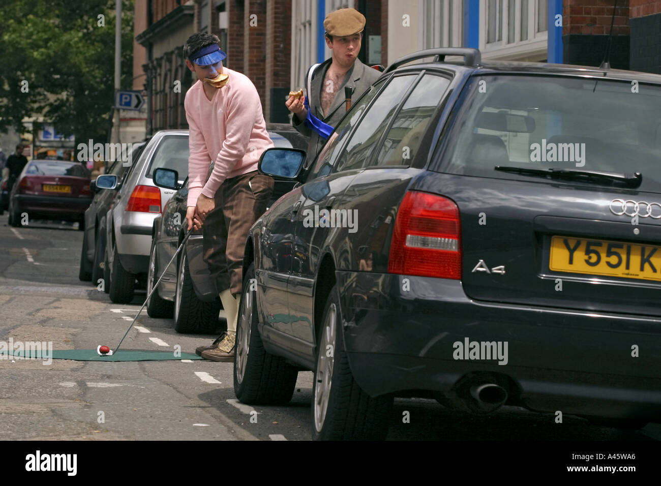 urban golf competitors take a snack while playing between cars at the first shoreditch urban open tournament in london Stock Photo