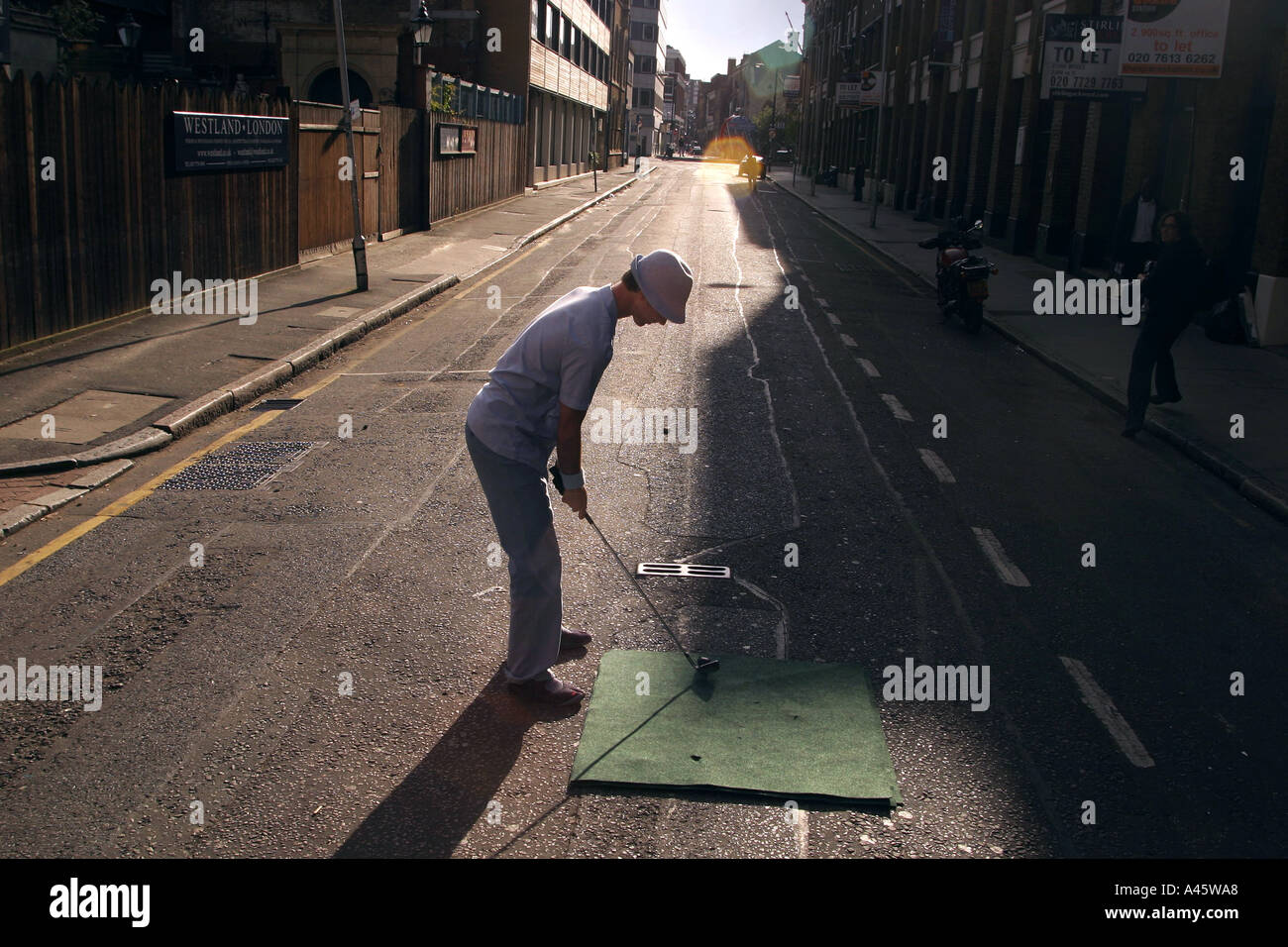 an urban golf competitor tees off in the street at the first shoreditch urban open tournament in london Stock Photo