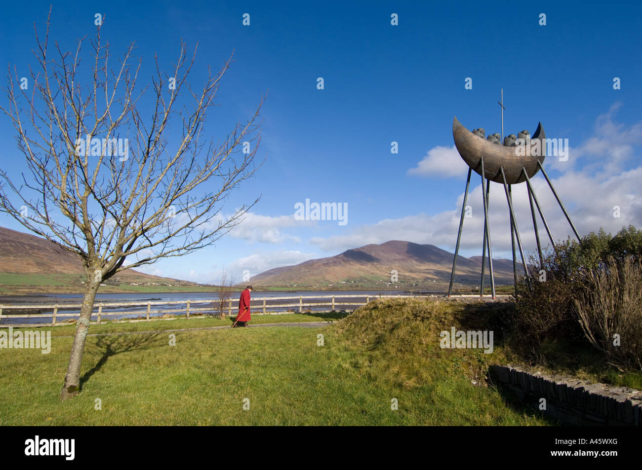 Elderly woman strolling near the Monks in a boat sculpture Caherciveen - County Kerry - Ireland - Europe Stock Photo