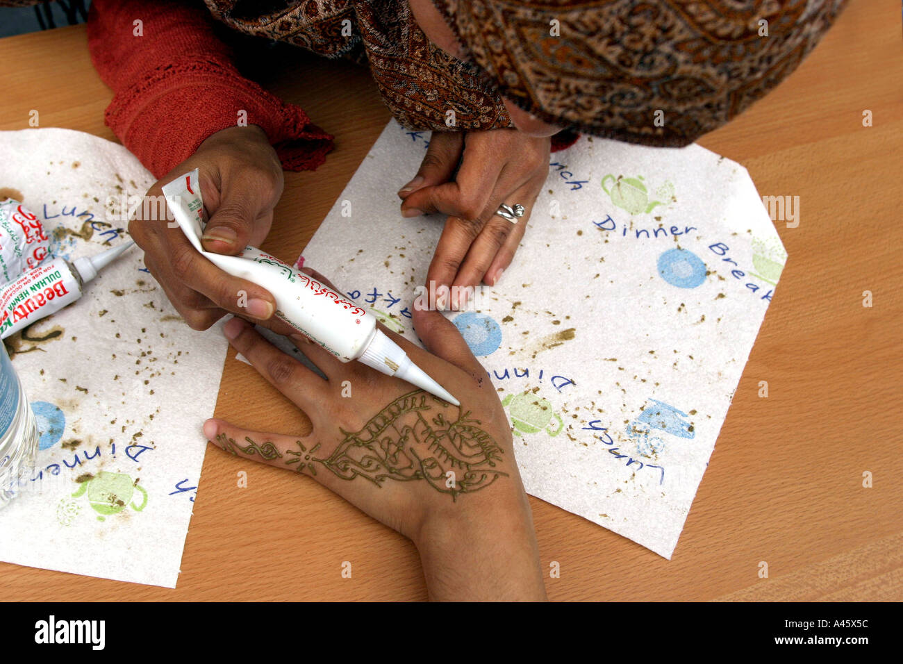 a muslim woman paints on a henna hand tattoo for customers at a fair to open the new london muslim centre an annex to the east london mosque in whitechapel in the east end of london Stock Photo