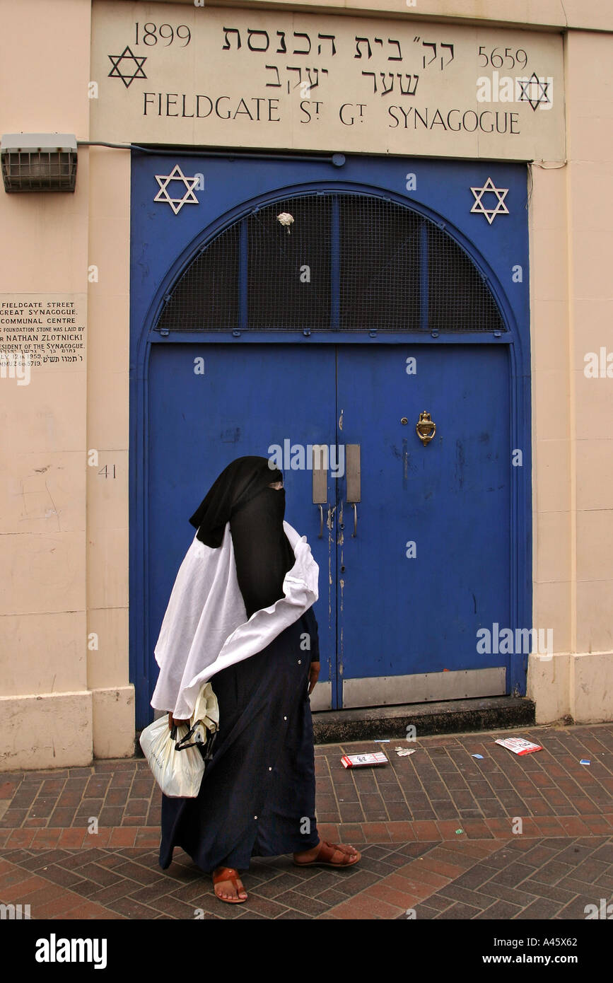 a muslim woman passes by a jewish synagogue at a fair to open the new london muslim centre an annex to the east london mosque in whitechapel in the east end of london Stock Photo