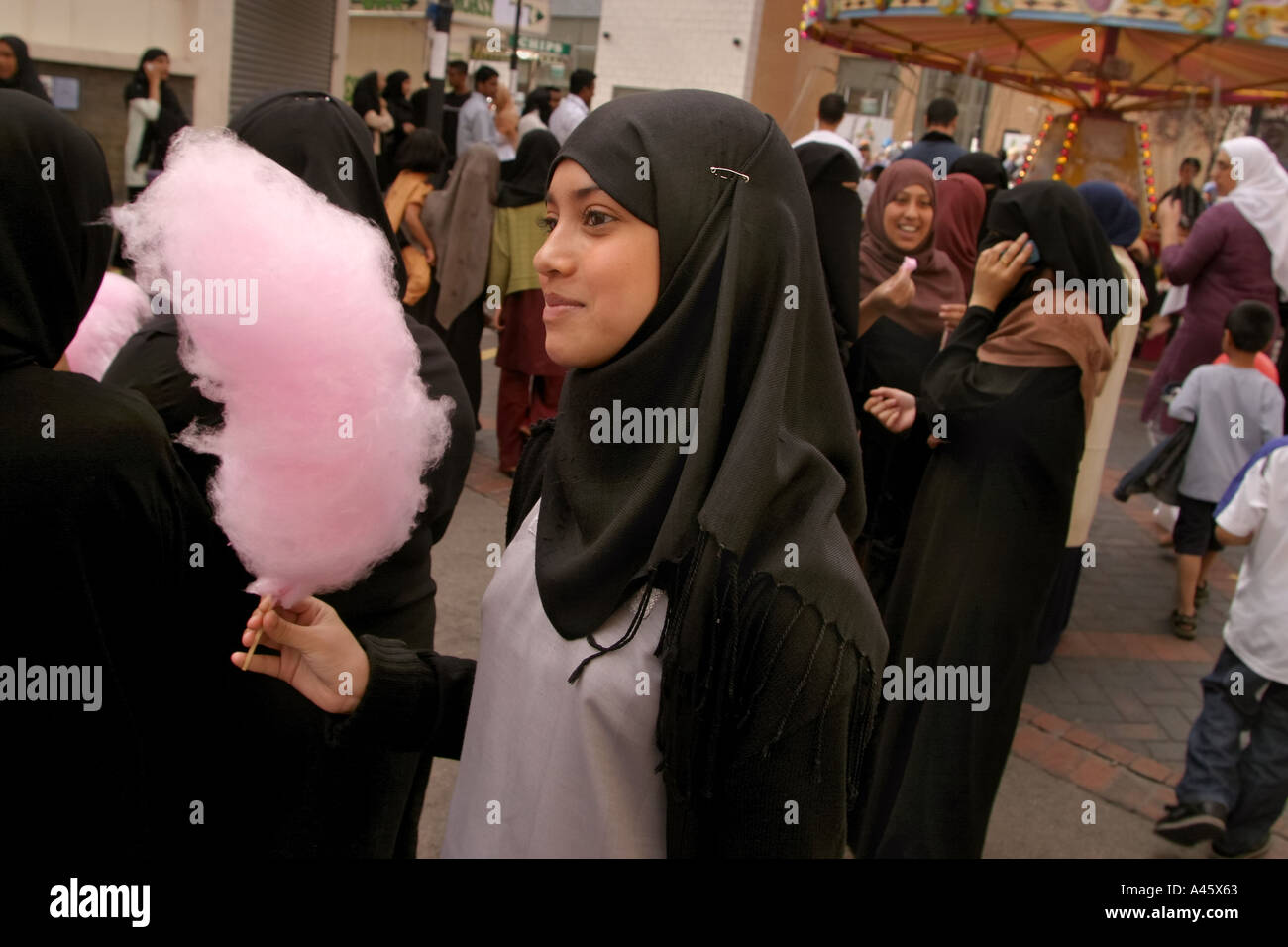 a muslim girl wearing a hijab headscarf carries candyfloss at a fair to open the new london muslim centre an annex to the east london mosque in whitechapel in the east end of london Stock Photo