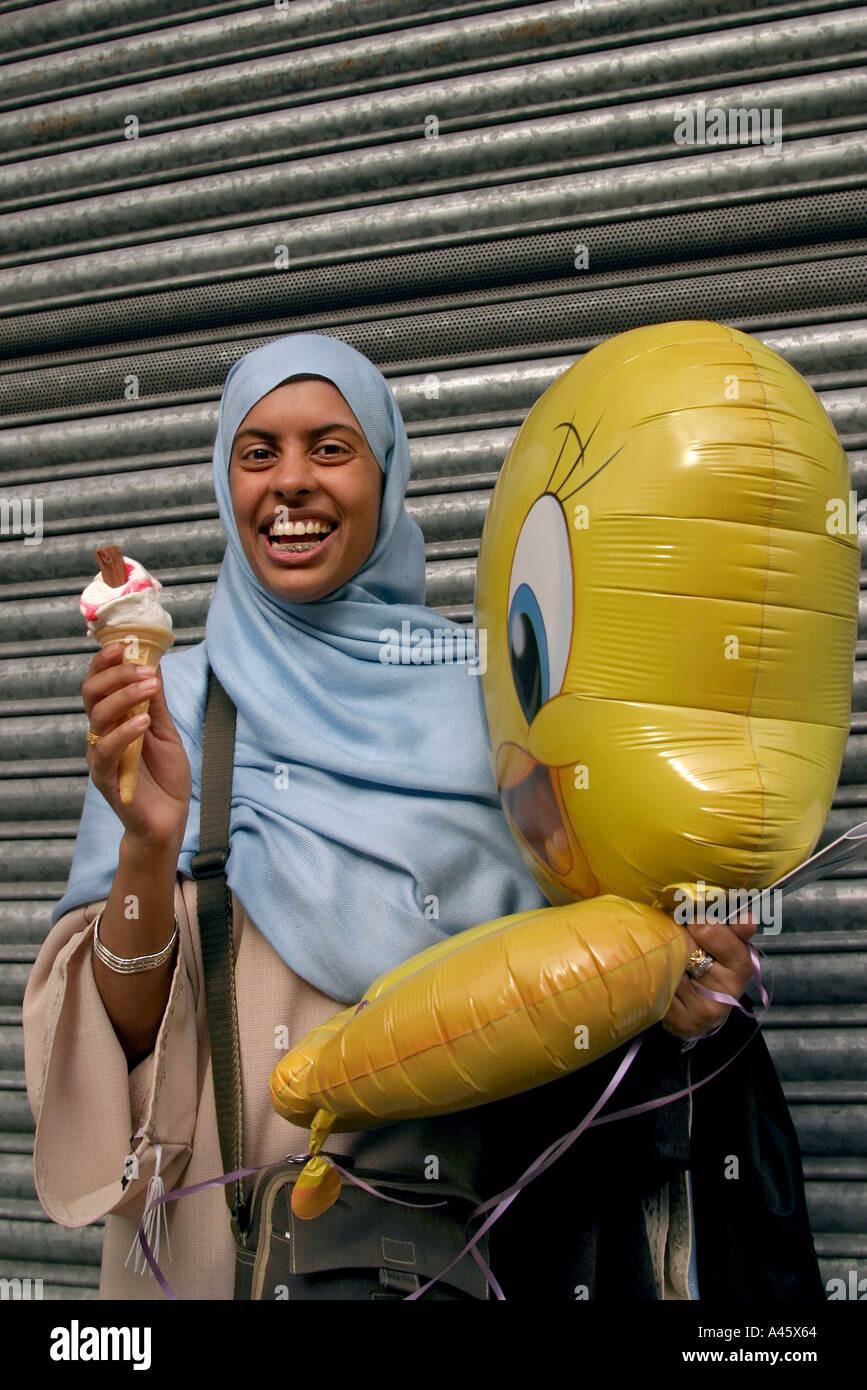 a muslim woman wearing the hijab headscarf carries an icecream and inflatable toy at a fair to open the new london muslim centre an annex to the east london mosque in whitechapel in the east end of london Stock Photo