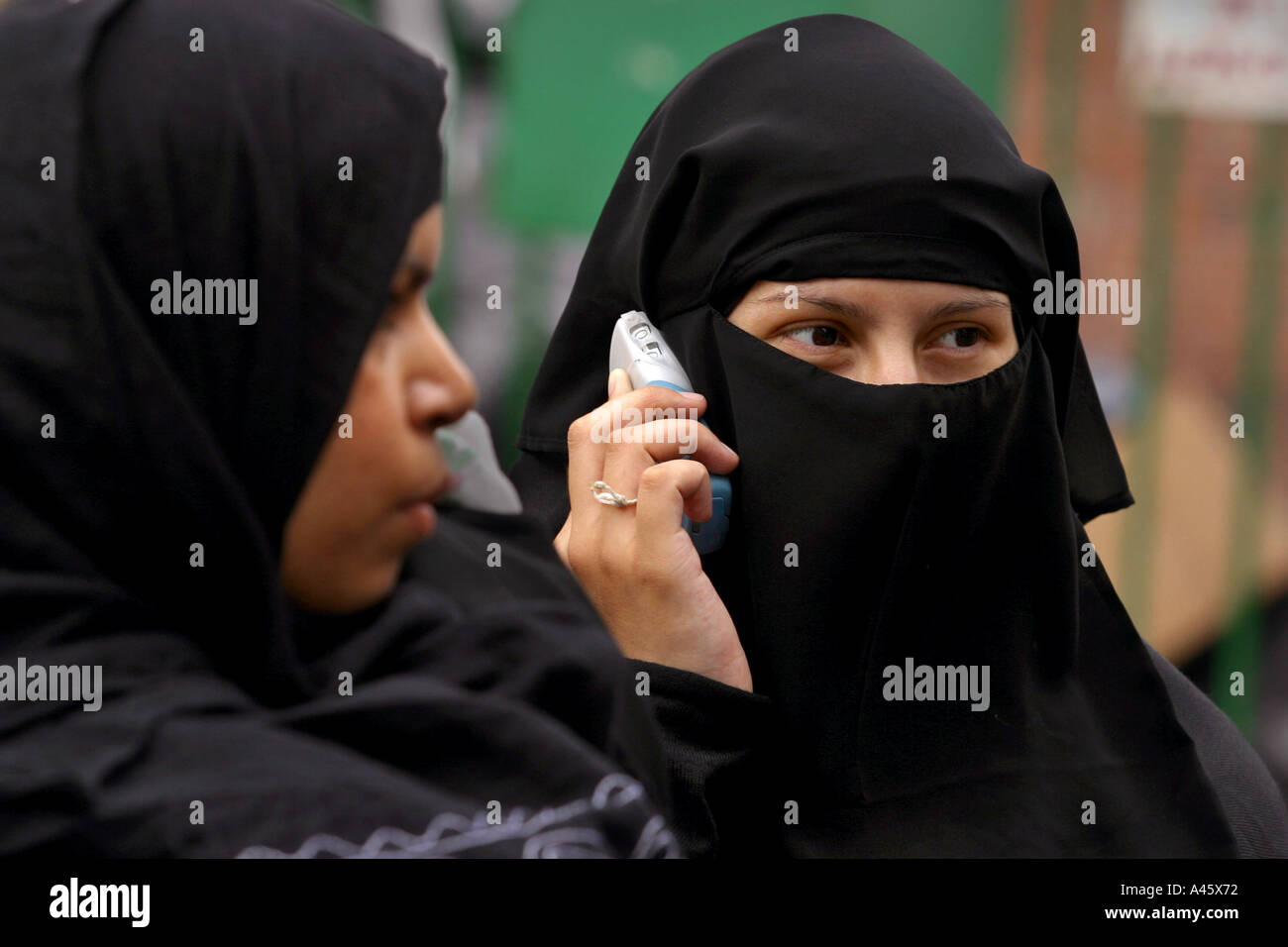 a muslim woman wearing a hijab headscarf and veil uses a mobile phone at a fair to open the new london muslim centre an annex to the east london mosque in whitechapel in the east end of london Stock Photo