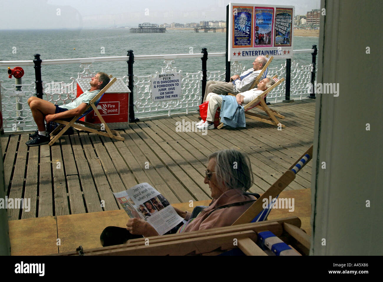 holidaymakers sit on deckchairs on brighton pier on the south coast of england Stock Photo