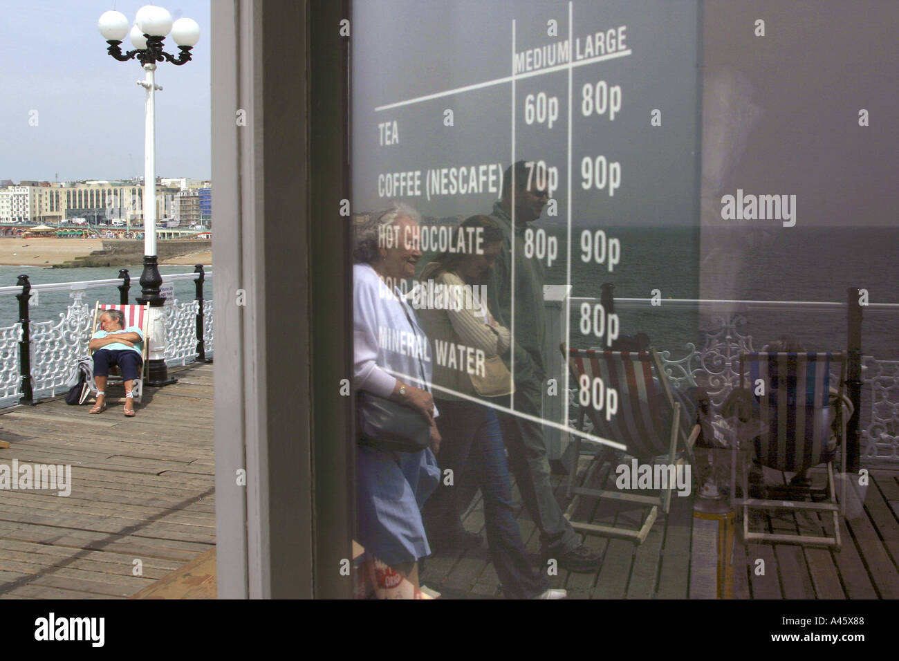 holidaymakers sit on deckchairs and walk along brighton pier on the south coast of england Stock Photo