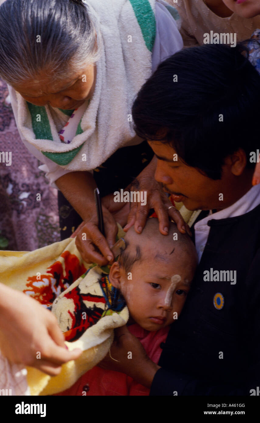 MYANMAR Burma South East Asia Religion Buddhism Ritual head shaving of young boy initiate monk Stock Photo