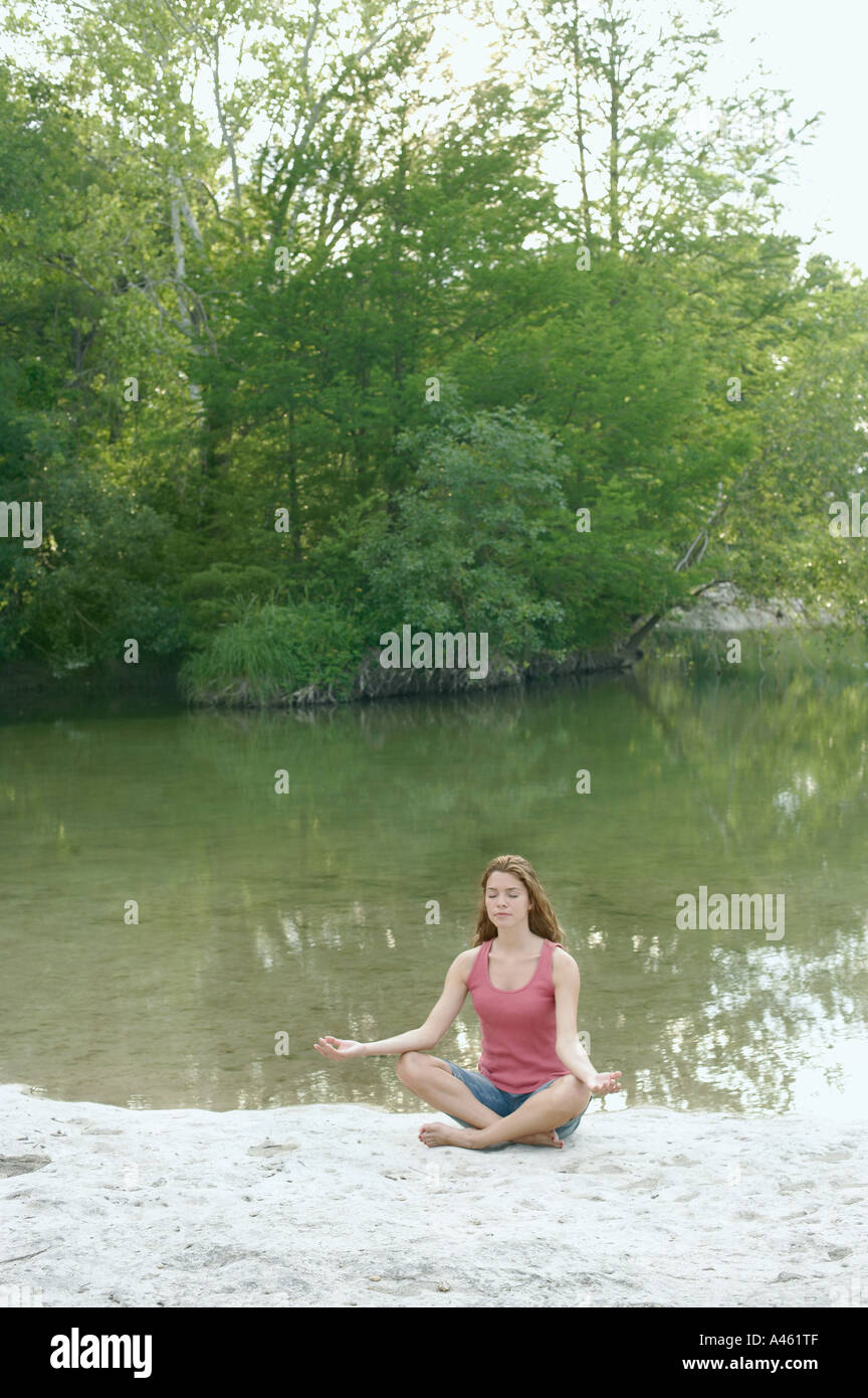 Woman in lotus position beside water Stock Photo