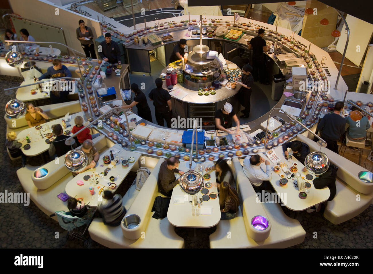 ENGLAND Kent Greenhithe Bluewater shopping mall Yo Sushi conveyor belt with people sitting at tables or booths and staff at work Stock Photo