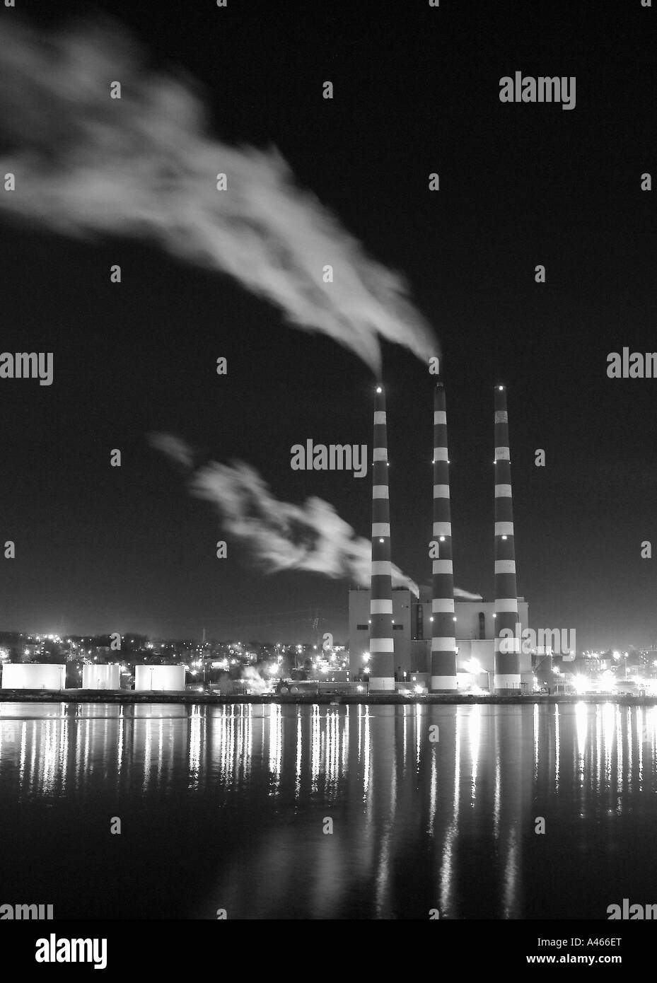 Night shot of Industrial smoke stacks reflecting on water. Stock Photo