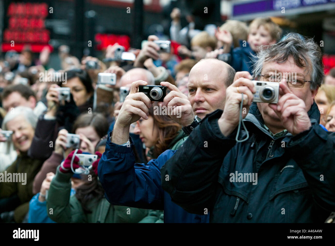 Crowd of spectators with digital cameras concentrating on taking ...