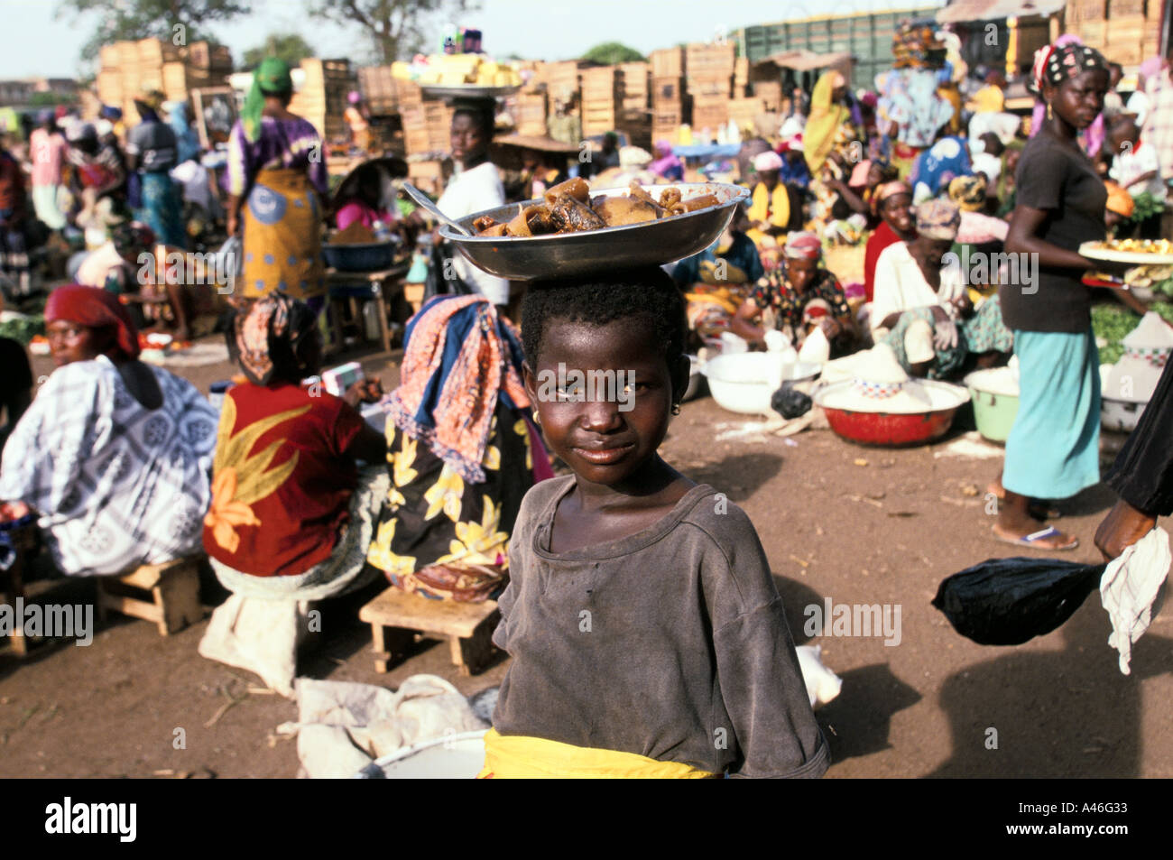 a street child balancing a tray of food to sell on her head working in the main market in tamale northern ghana Stock Photo