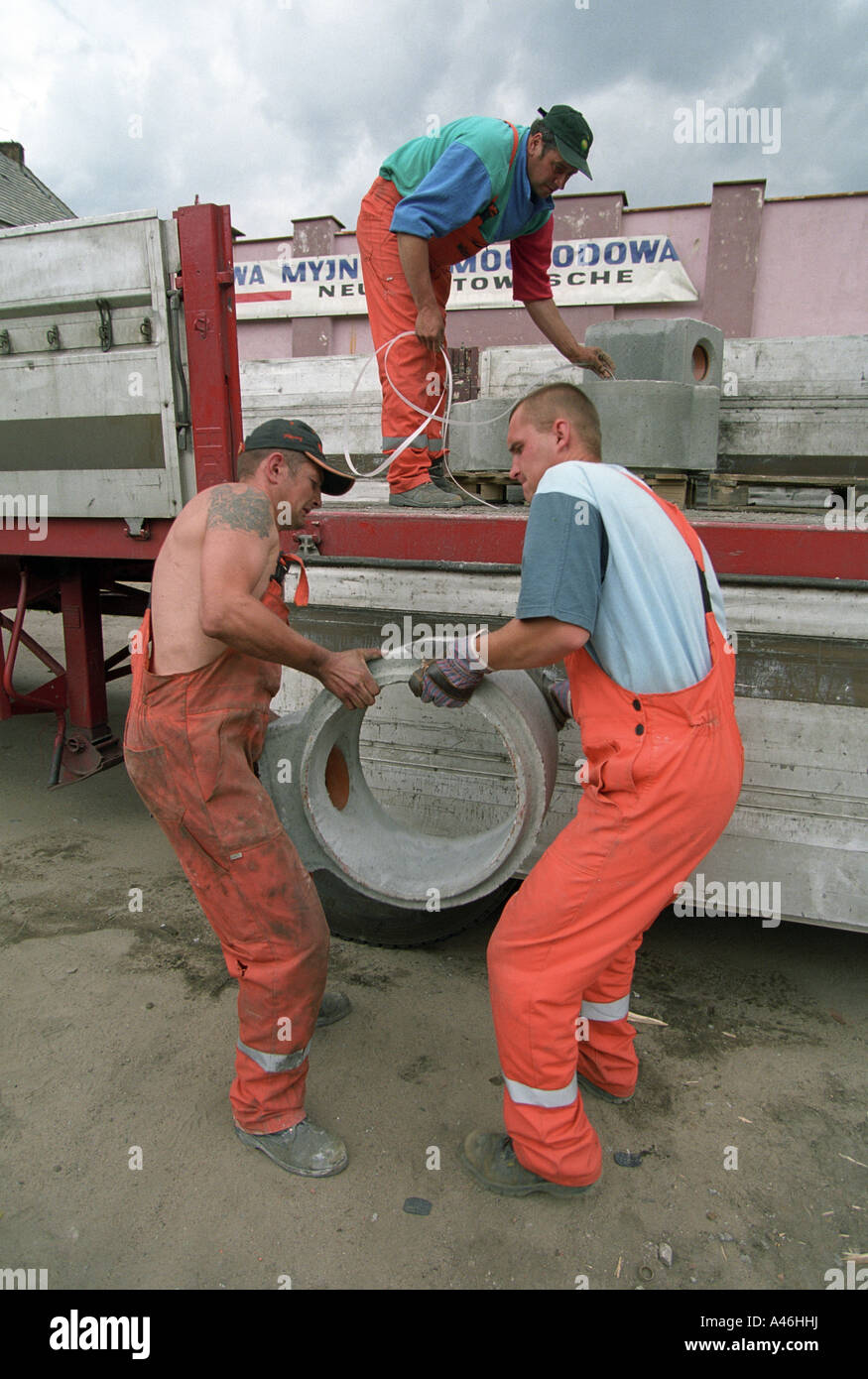 Construction workers lifting a concrete part from a semitrailer