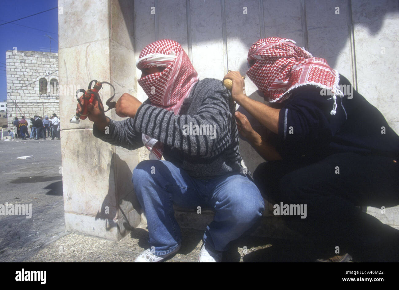 Palestinian youths throw stones with catapults at Israeli Defence Force (IDF) soldiers during a street clash in Bethlehem. Stock Photo