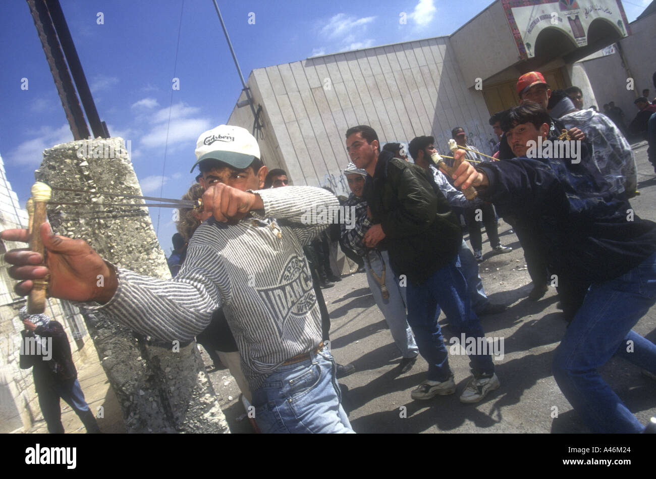 Palestinian youths throw stones with catapults at Israeli Defence Force (IDF) soldiers during a street clash in Bethlehem. Stock Photo