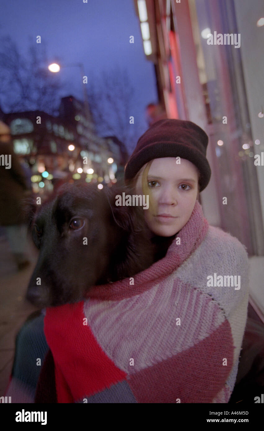 A homeless teenager sits with her dog on Charing Cross Road in London Stock Photo