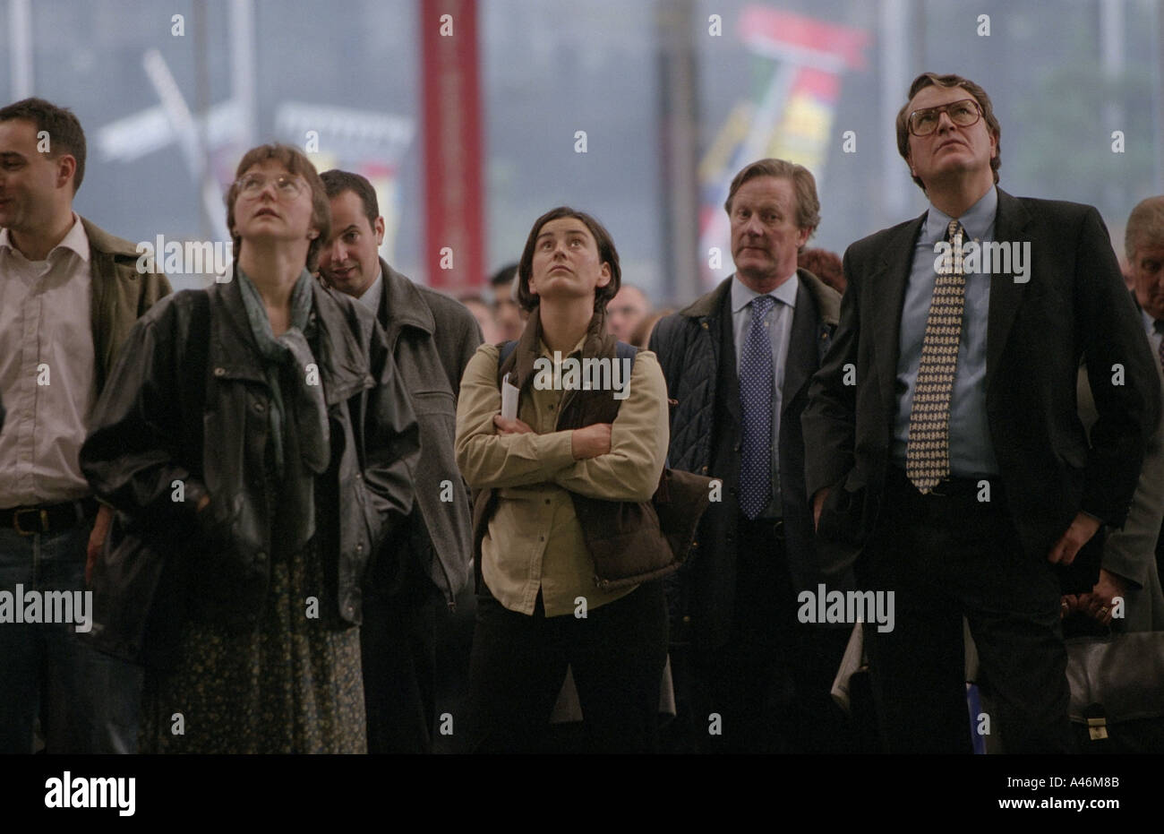 Commuters look up at train timetable announcements at Euston Railway Station in London Stock Photo