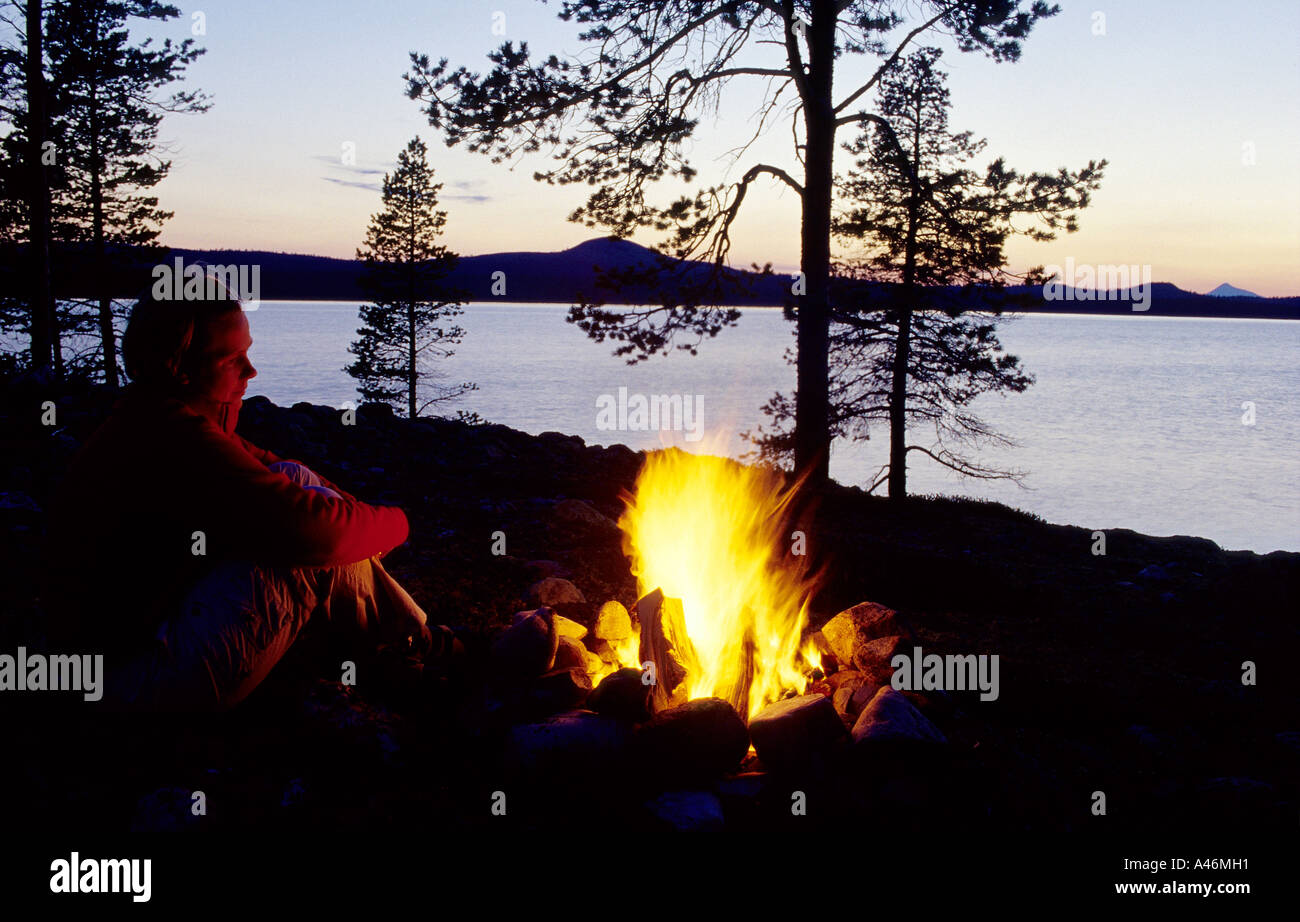 Hiker sitting by an open fire. Lake Femunden, Norway Stock Photo