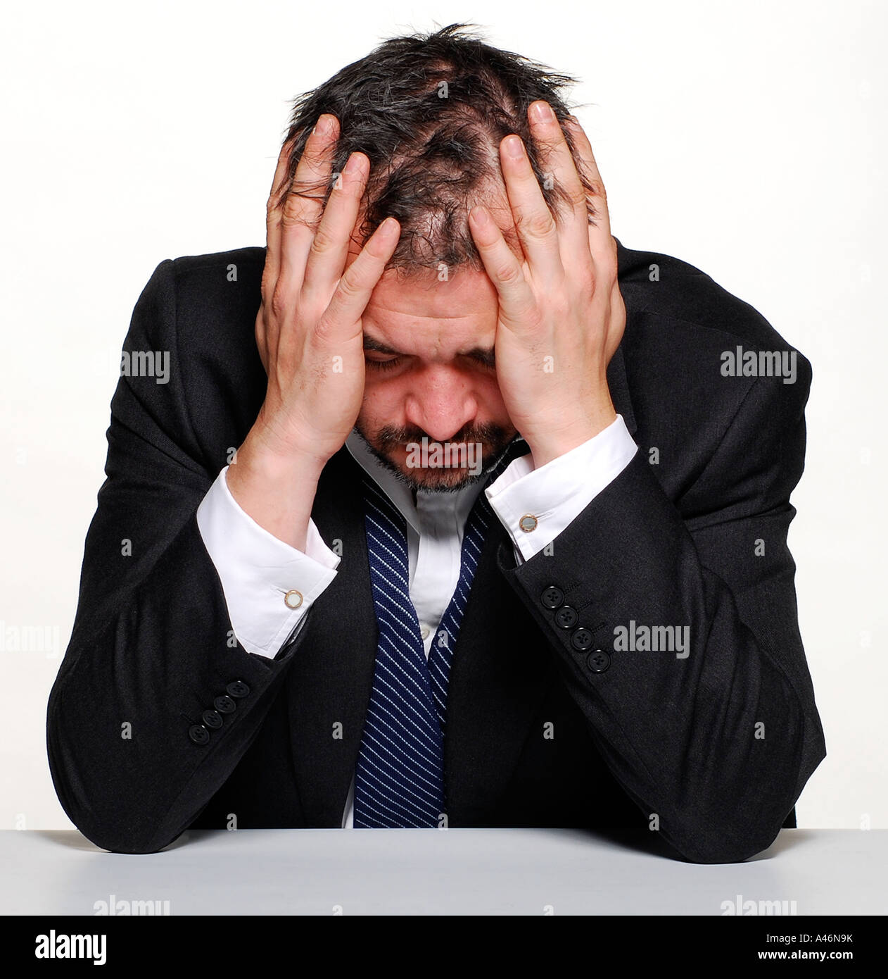 An emotional man sits holding his head with his hands. Picture by ...