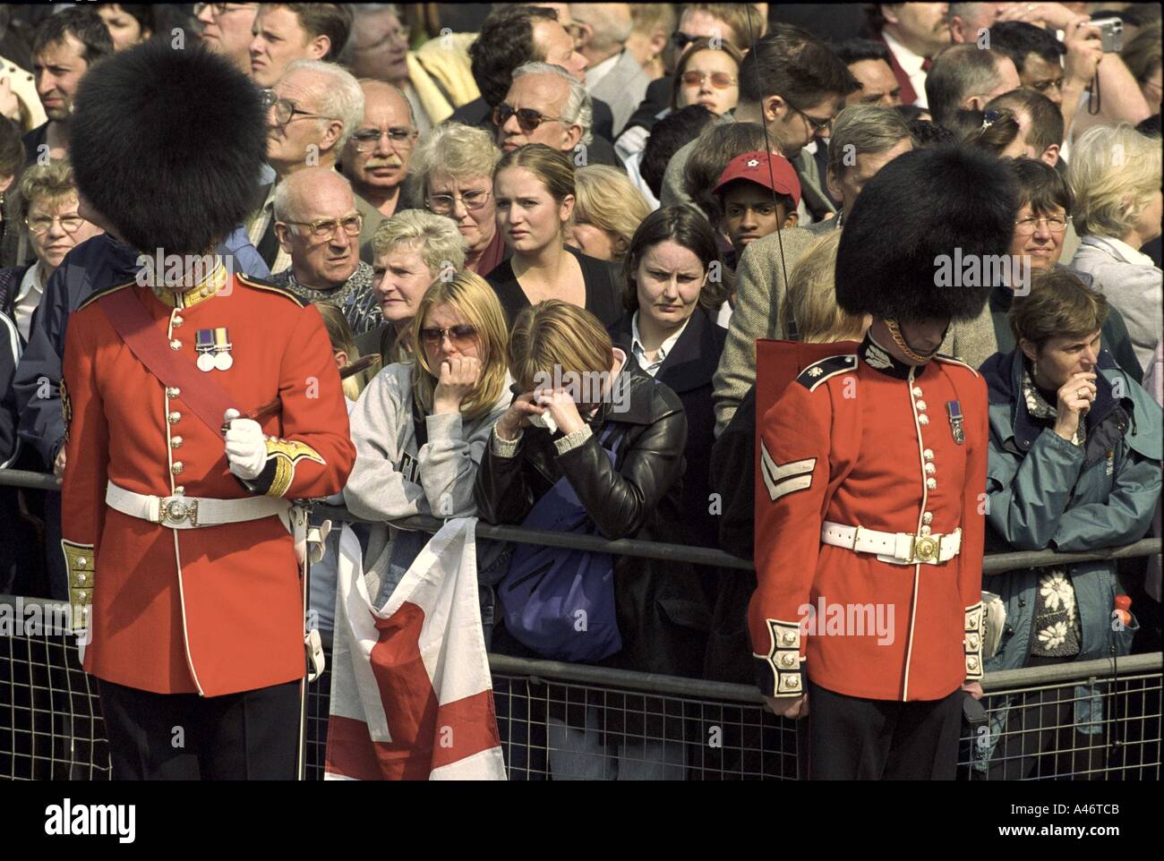 Crowd of people line the route of the Queen Mother s funeral procession guarded by members of the Guards regiment The Mall  Stock Photo