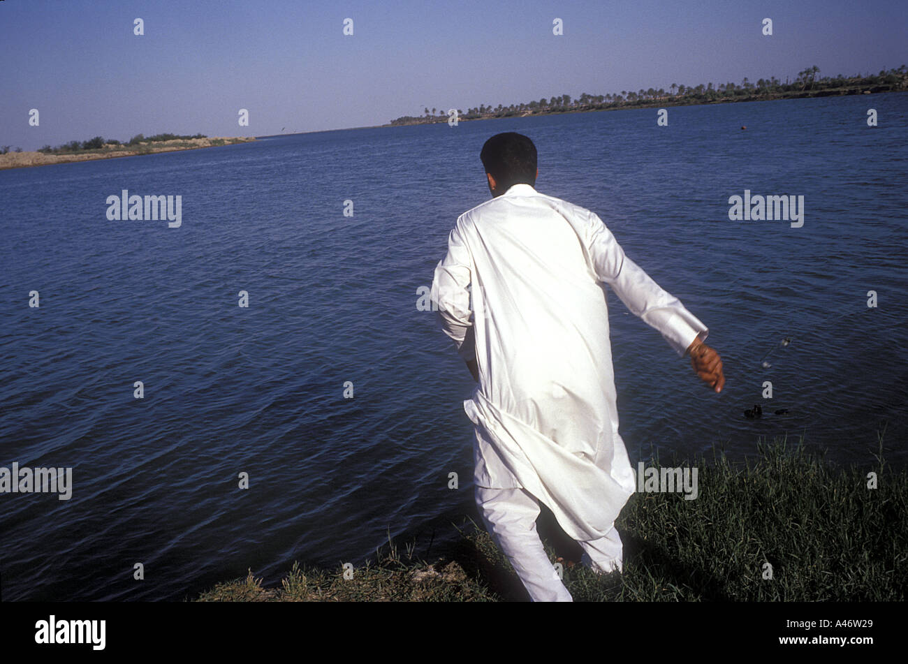 An Iraqi man fishes with a line at the confluence between the Tigris and Euphrates rivers called Al-Qurnah (Qurna) Basra, Iraq Stock Photo