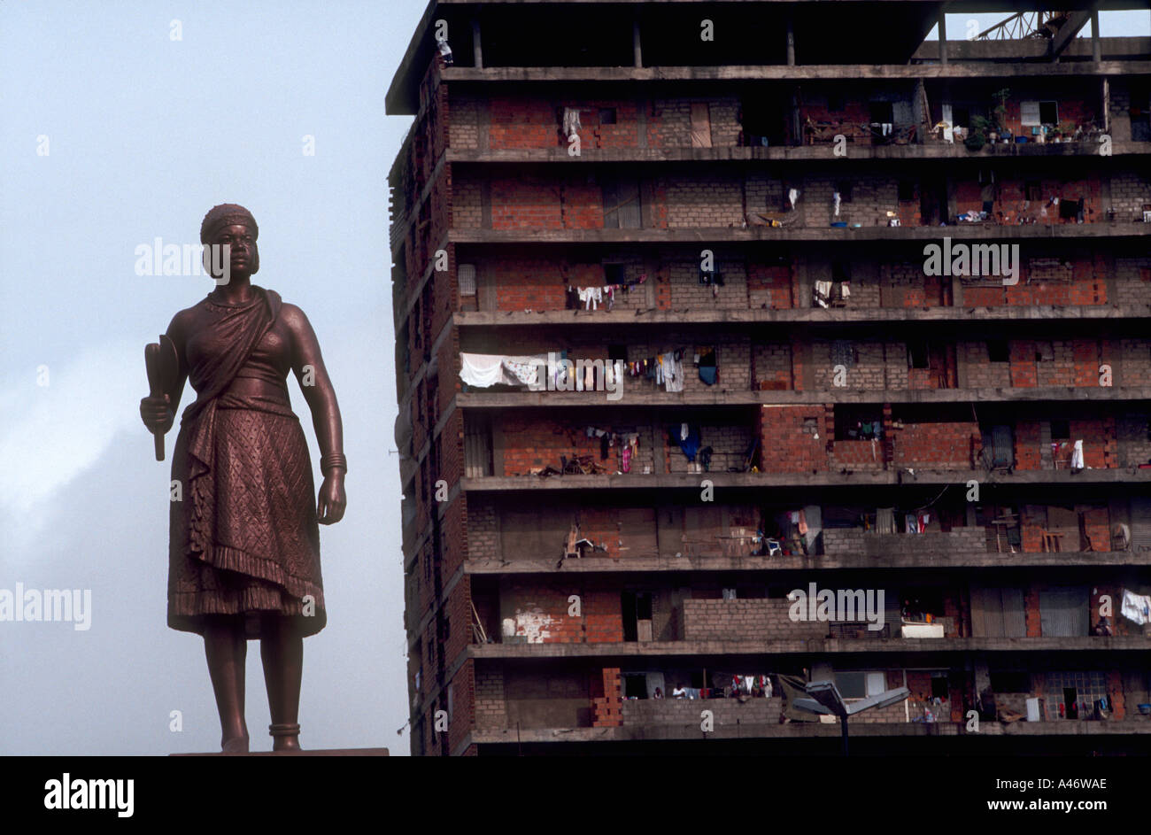 A run down block of flats stands behind a statue of queen nzinga in kinixixi square a warrior queen who opposed the Portuguese Stock Photo