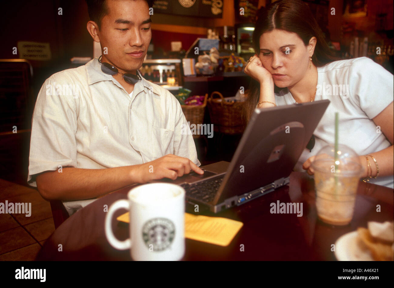 John and Shane Vu from America surf the internet with a laptop at a Starbucks cafe on Old Broad Street in the City of London, UK Stock Photo