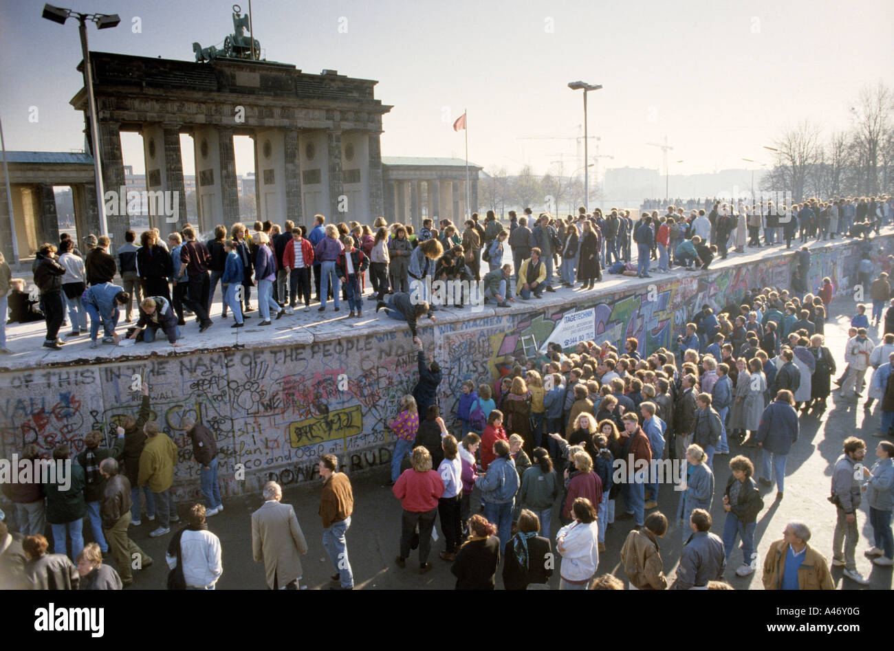 Fall of the Berlin Wall: people from East and West Berlin climbing on the Wall at the Brandenburg Gate, Berlin, Germany Stock Photo