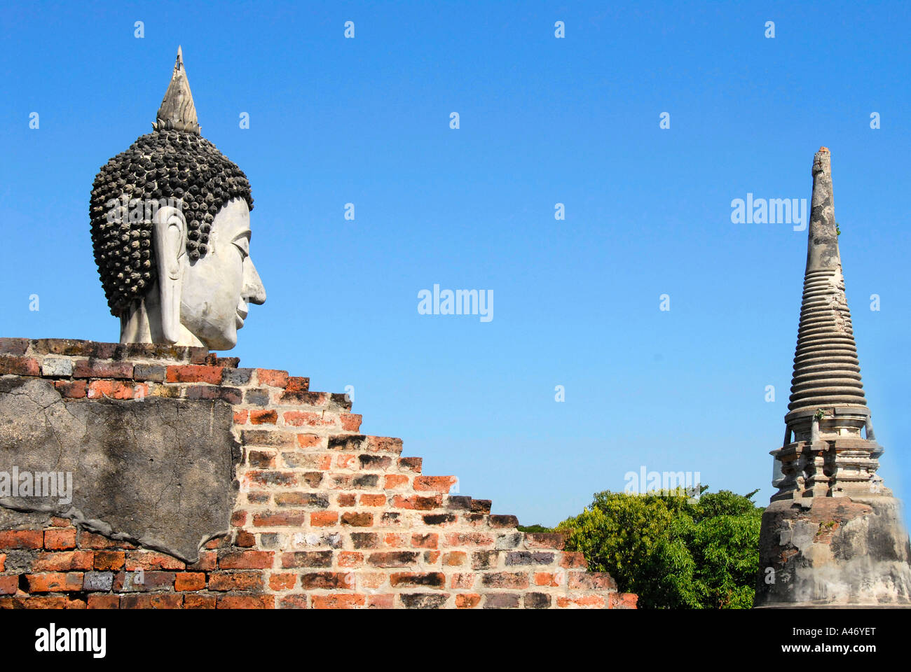 Head of a Buddha figure facing temple tower Wat Yai Chai Mongkol Ayutthaya Thailand Stock Photo