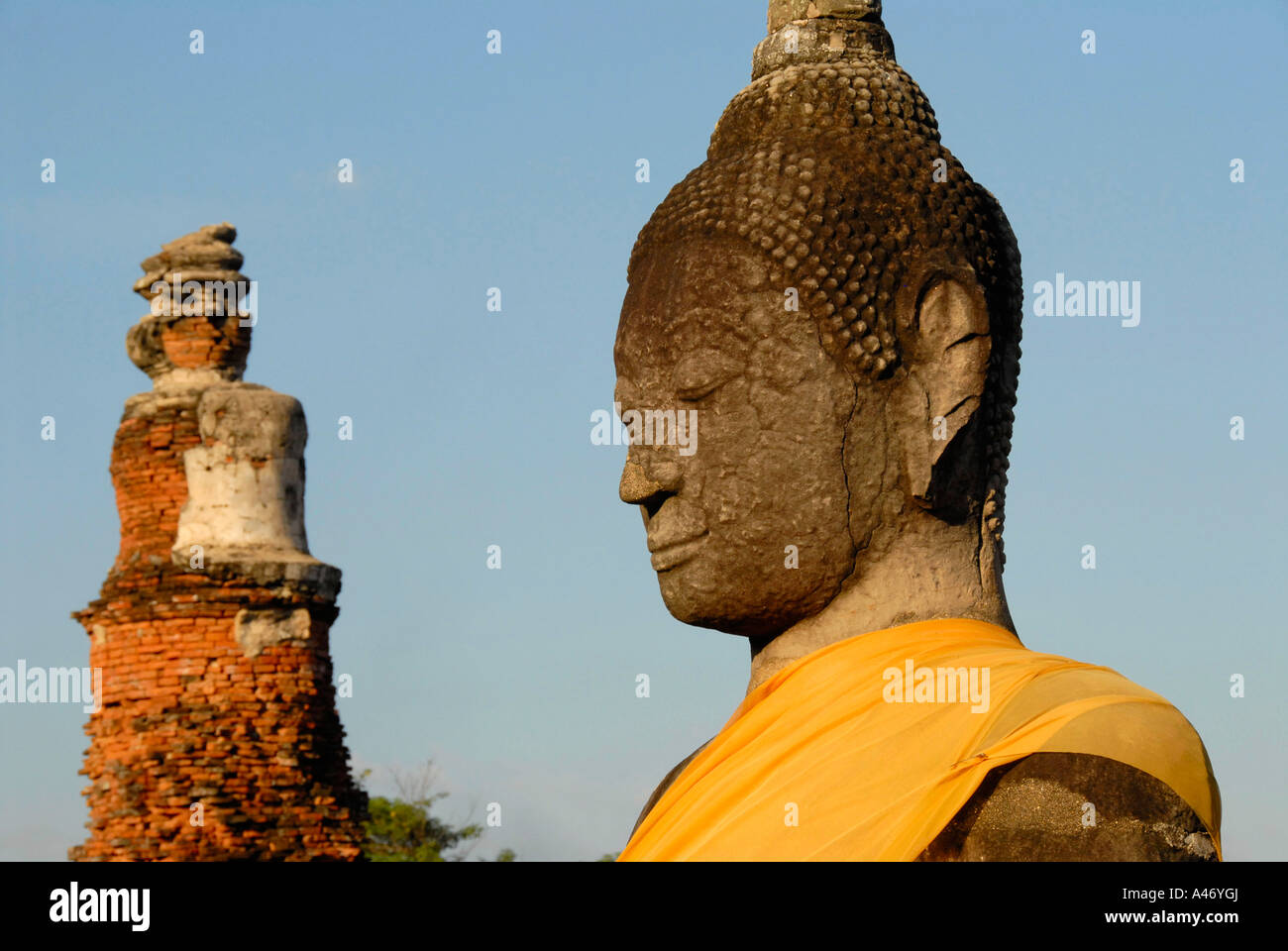 Head of a Buddha figure facing a brick tower Wat Mahathat Ayutthaya Thailand Stock Photo