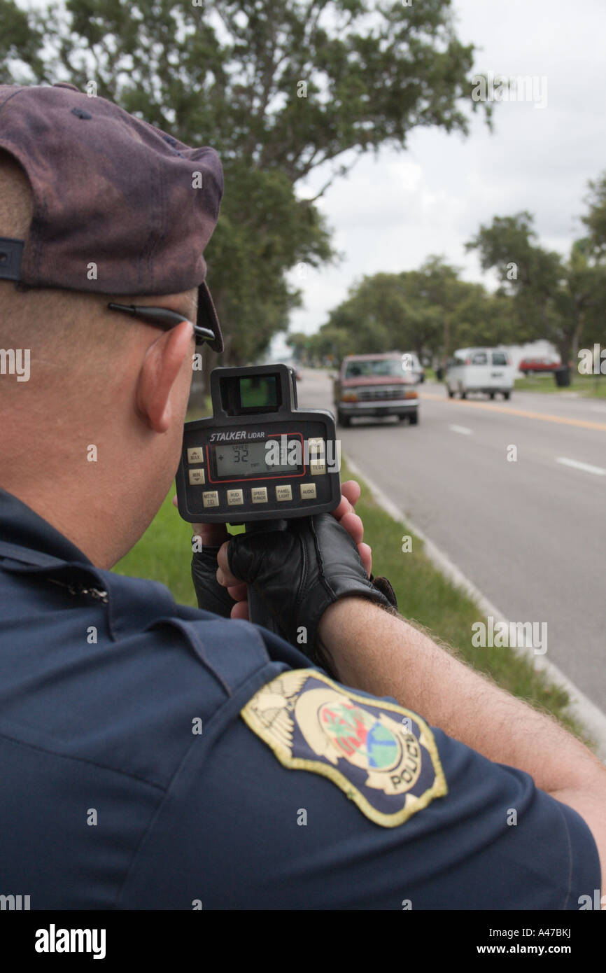 Motorcycle Police Officer Using a Laser Gun to Measure Speed in a Residential Neighborhood Stock Photo