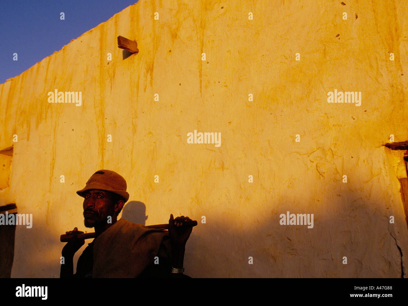 A farmer pauses by a wall in the late afternoon sun in the village of Ali Shahin self declared independent country of Somaliland Stock Photo