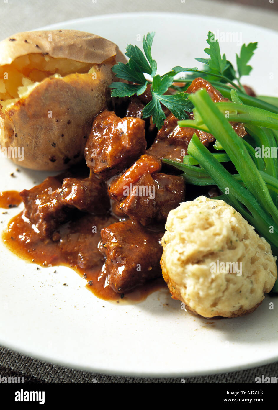 A plate of beef stew dumpling and a jacket potato editorial food Stock