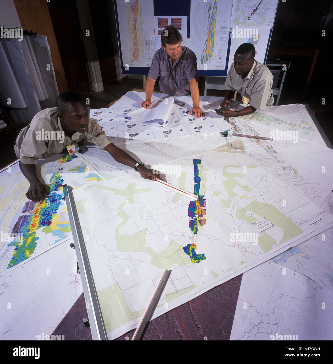 Geologists examining maps and discussing exploration targets, geology