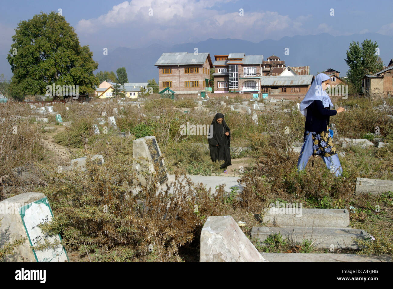Women walk through Srinagar's main graveyard in Kashmir in India Stock Photo