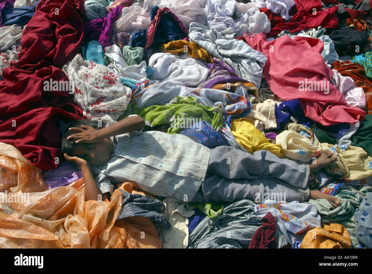 A young boy rests in a pile of clothes given as aid after the tsunami hit in Nagapattinam in India Stock Photo