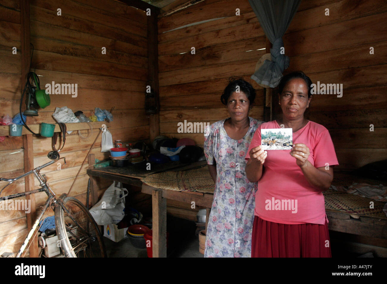 Two sisters display a photograph taken of their destroyed house almost one year after the tsunami struck Sri Lanka Stock Photo