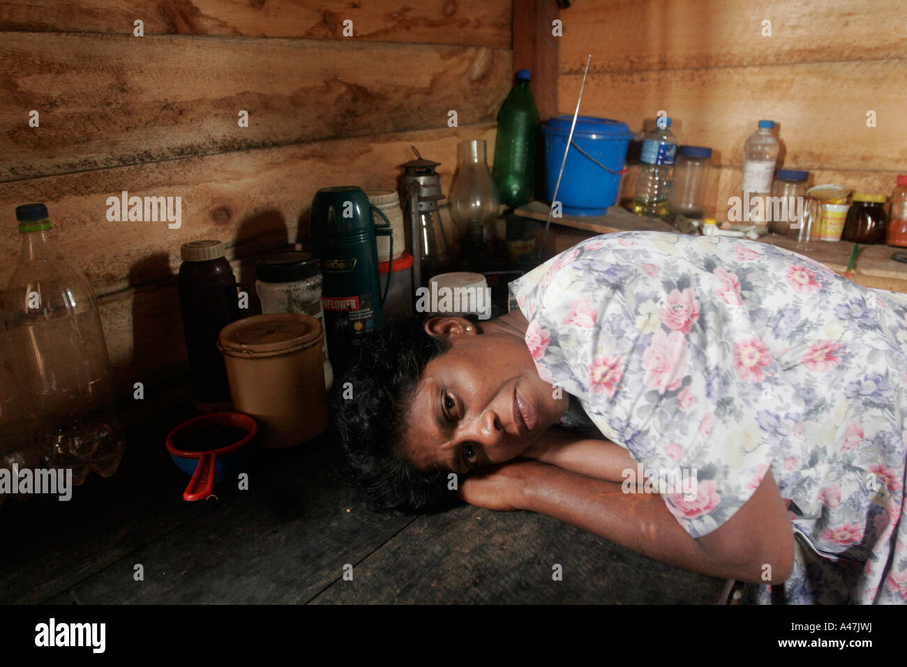 A woman rests inside her makeshift shelter where she still lives almost one year after the tsunami struck Sri Lanka Stock Photo