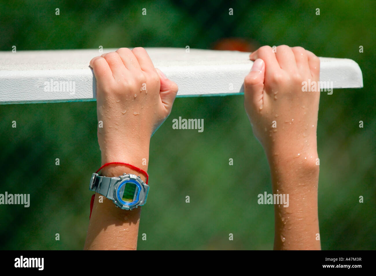 Hands grasping edge of diving board Stock Photo