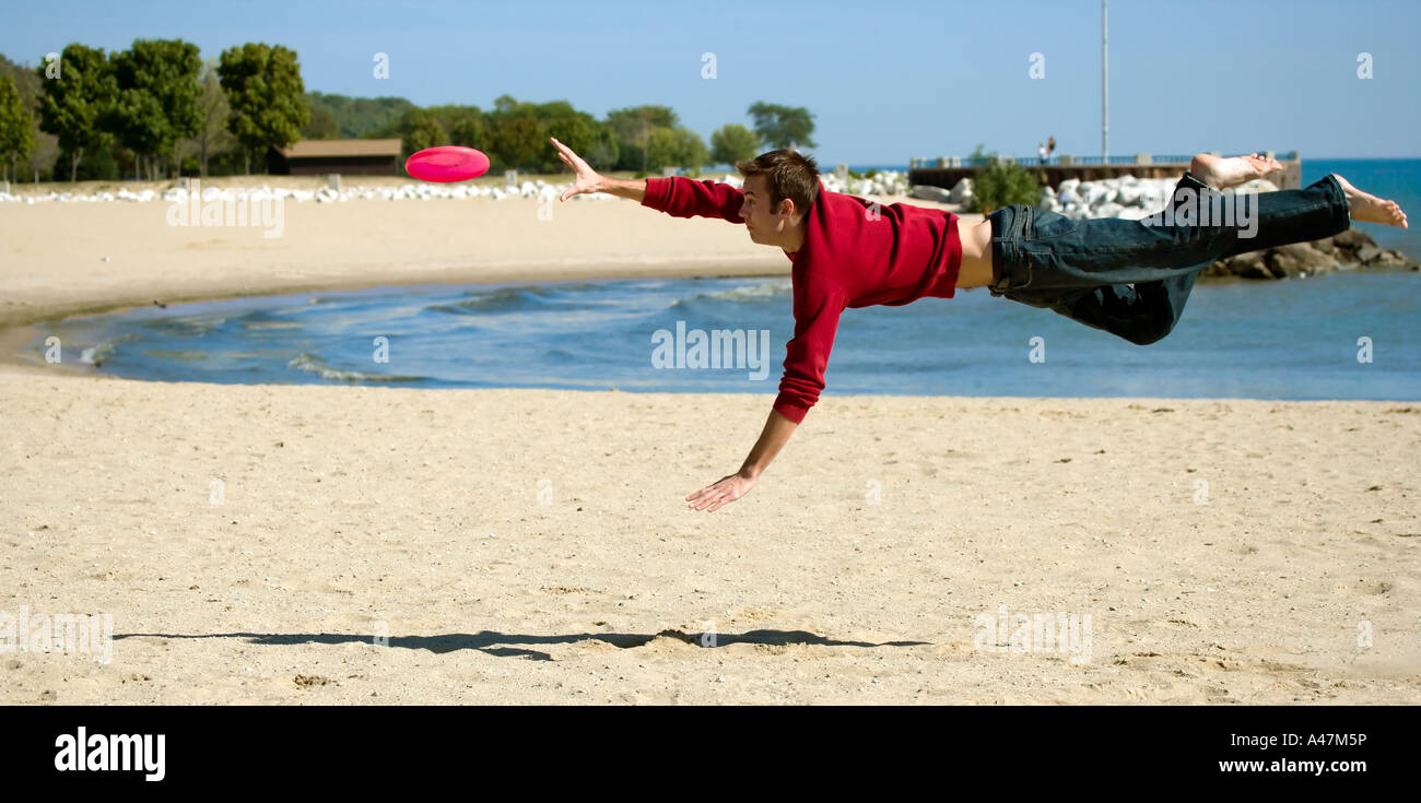 Young man catching Frisbee in midair Bradford Beach Lake Michigan Milwaukee Wisconsin USA Stock Photo