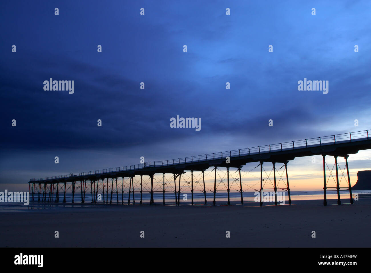 Low key image of old pier on beach at Saltburn in North Yorkshire in pre dawn light Stock Photo