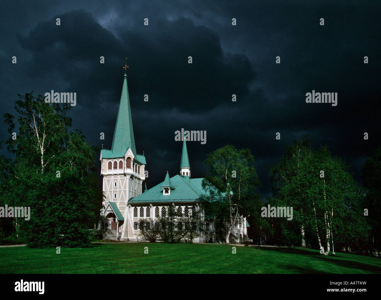Dramatic black clouds gather behind a traditional wooden church in the high arctic Swedish town of Jokkmokk Stock Photo
