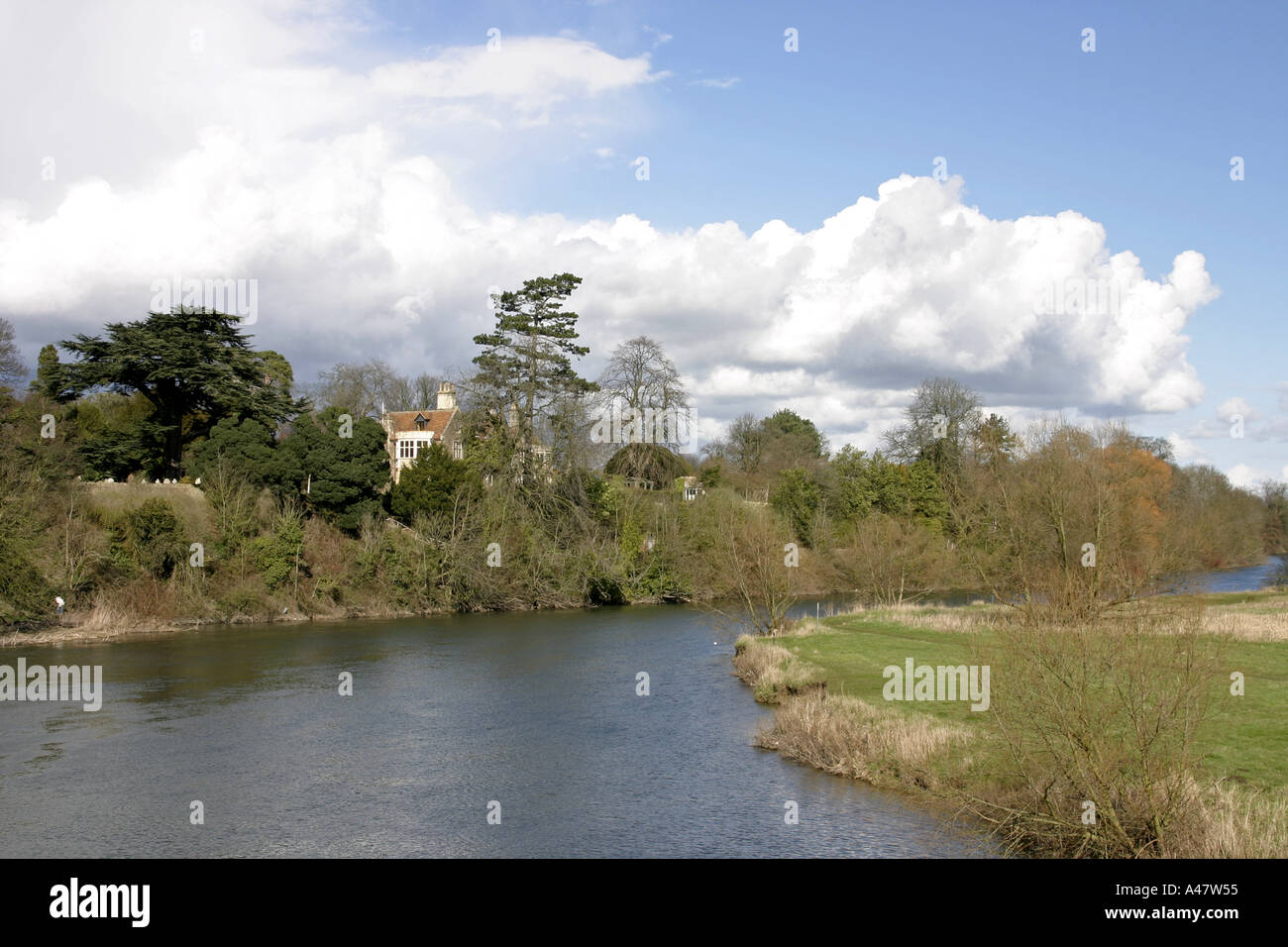 A Bend in The River Thames with a house behind some trees in the summer at Clifton Hampden Oxfordshire England Stock Photo
