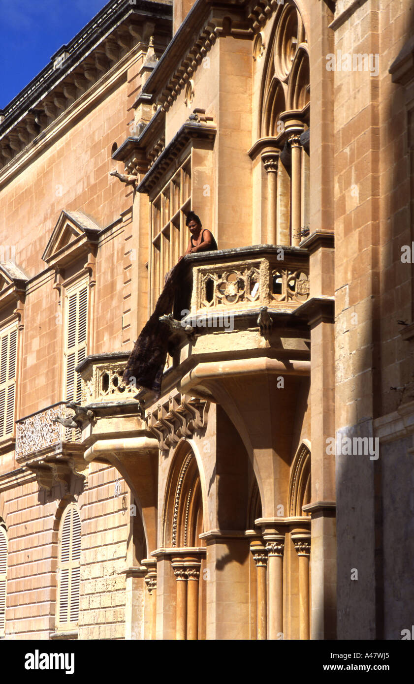 Woman on a balcony beating a carpet Stock Photo