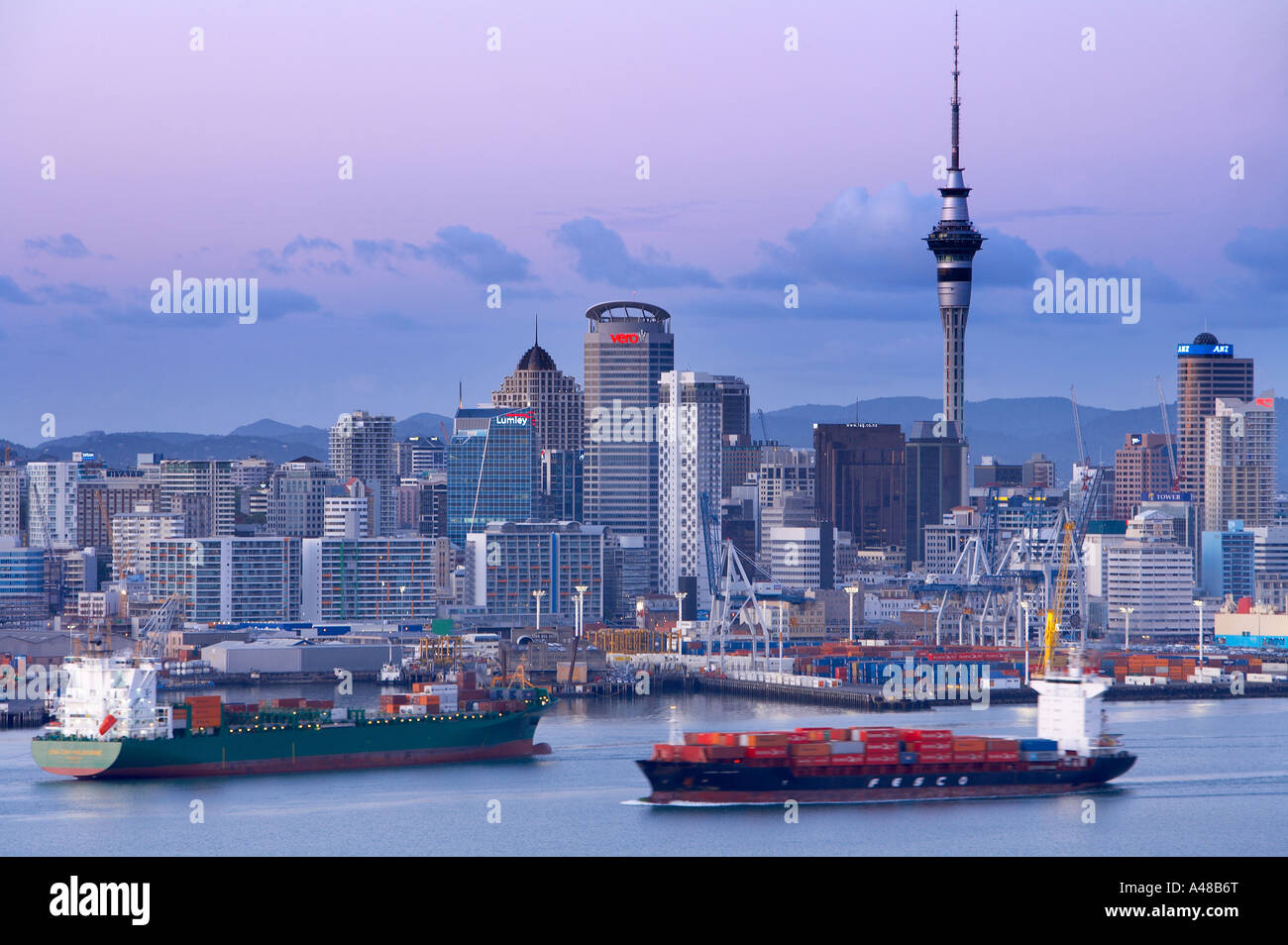 the City Centre with the Skytower waterfront docks with two container cargo ships Auckland New Zealand NR Stock Photo