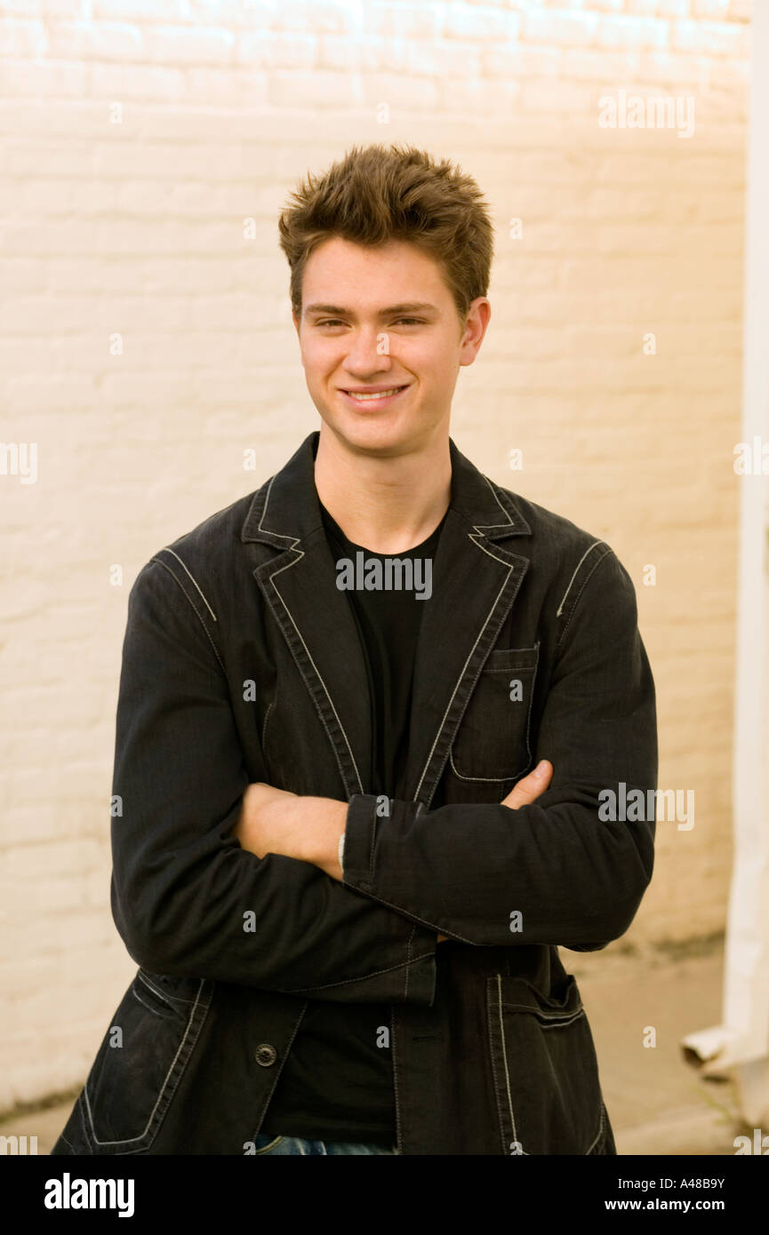 Young man standing with arms crossed, smiling Stock Photo - Alamy
