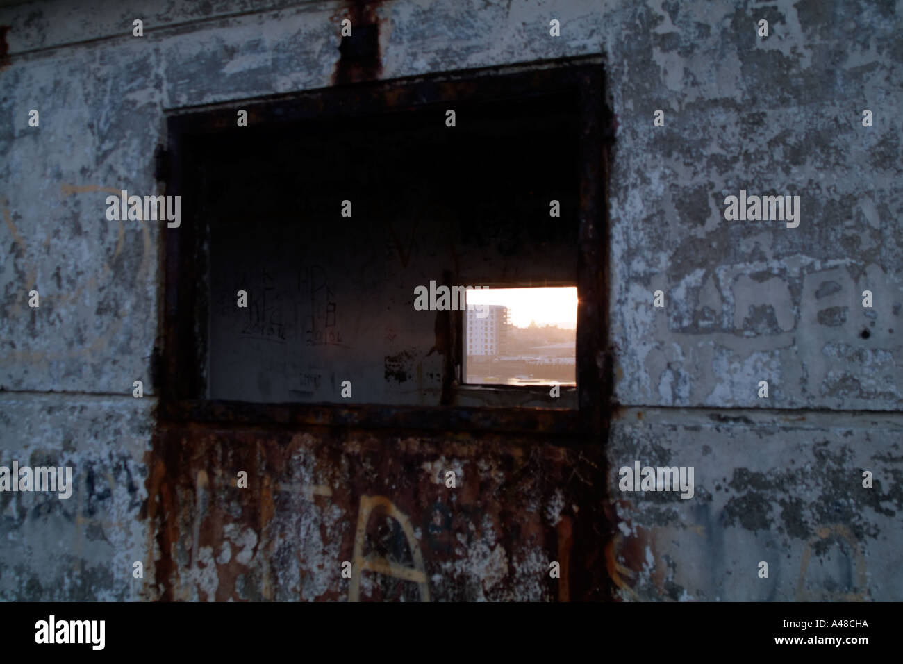 Sunny view of harbour and a block of flats through a derelict building