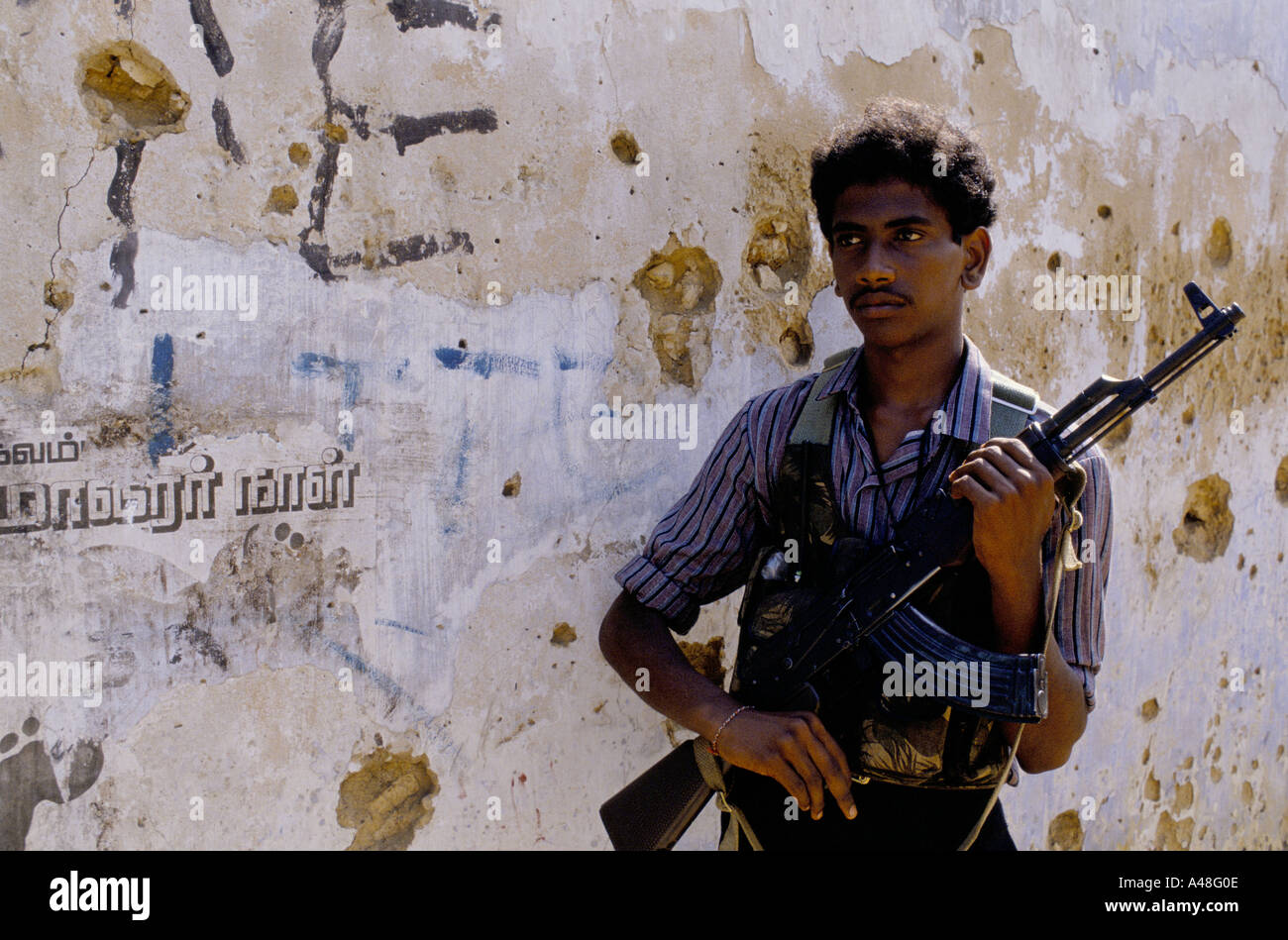 A Tamil tiger commando poses in front of a wall of political slogans Jaffna Peninsula Sri Lanka Stock Photo